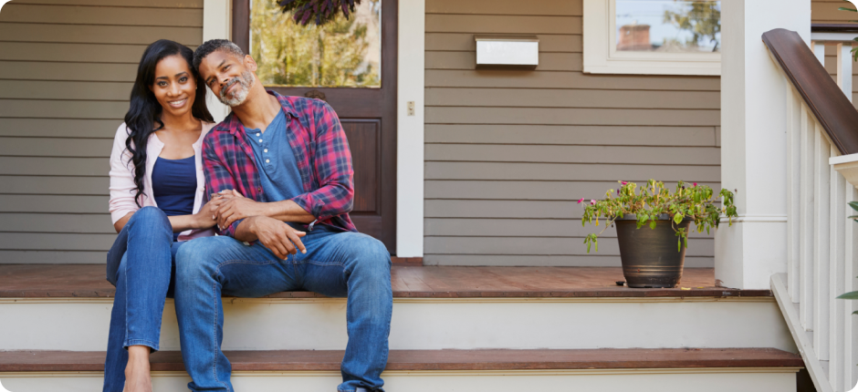 Smiling couple sitting on home porch steps after securing their mortgage with Key Mortgages.