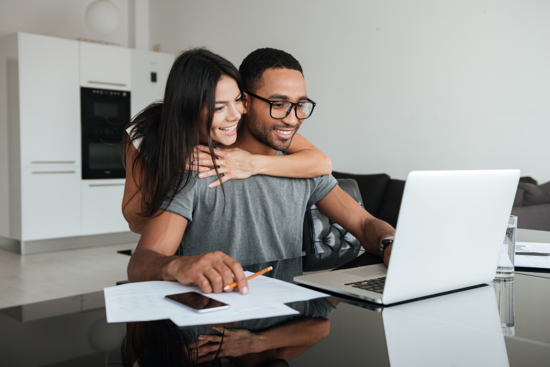 Smiling couple on laptop researching home loan options with Key Mortgages.